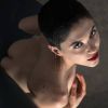 A girl with short hair and red lips poses artistically, partially nude, exuding confidence and elegance.