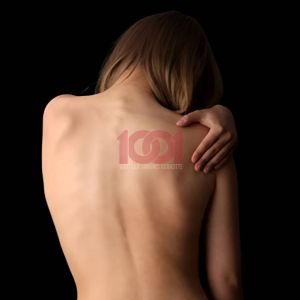A back view of a person with long hair, gently holding their shoulder, against a dark background.