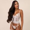A woman poses confidently in a delicate white lingerie set against a neutral background.