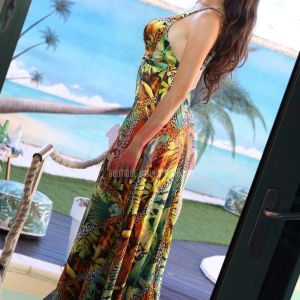 Una donna in abito lungo colorato si mostra su un balcone con un bellissimo sfondo tropicale.