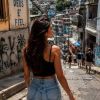 A woman walks down a colorful street with a view of houses on the hillside, embodying a vibrant urban atmosphere.