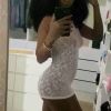 A person takes a mirror selfie, wearing a delicate lace outfit, with a stylish backdrop of clothing and accessories.