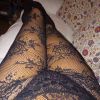 Immagine di gambe in collant trasparente neri, sdraiate su un divano bianco con cuscini colorati.