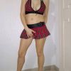 A person in a red plaid outfit poses, featuring a top and a mini skirt, paired with high heels.