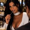 A woman in a white dress elegantly holds a spoon, gazing captivatingly at a dinner companion in a fine restaurant.