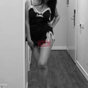 Immagine in bianco e nero di una donna che indossa un vestito elegante, appoggiata a una porta.