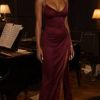 Elegante figura femminile in abito bordeaux, accanto a un pianoforte, in un ambiente intimo e raffinato.