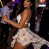 A woman dances in a lively club, wearing a floral skirt and enjoying the vibrant atmosphere.